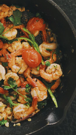 A vibrant skillet filled with sautéed shrimp, garlic, and cherry tomatoes.