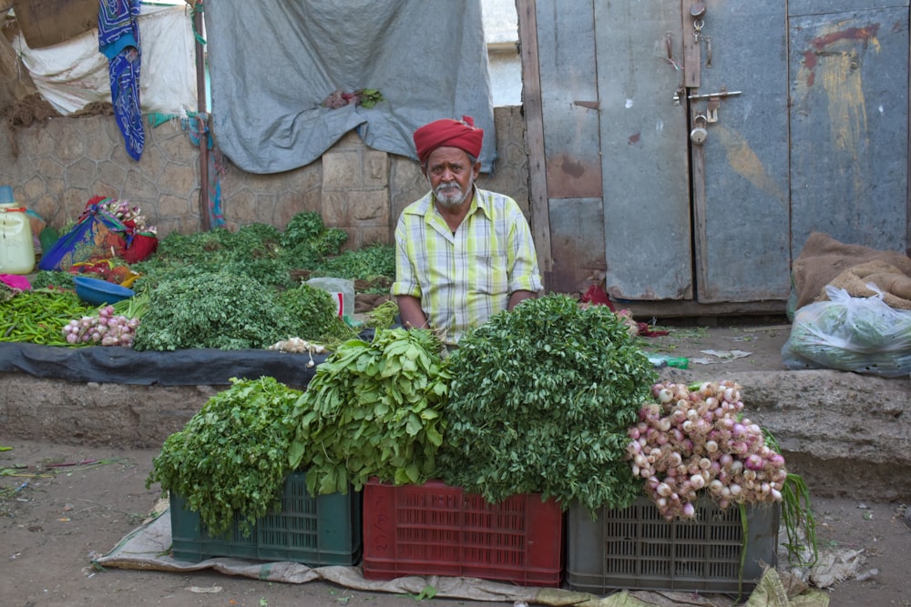 man in white dress shirt and red hat standing in front of green plants