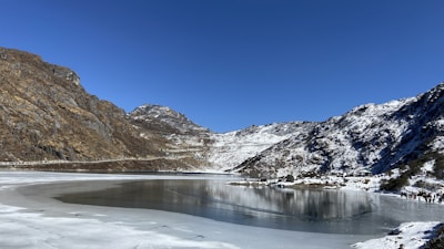 brown and white mountains near lake under blue sky during daytime