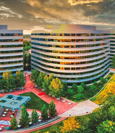 high rise building near green trees under white clouds during daytime