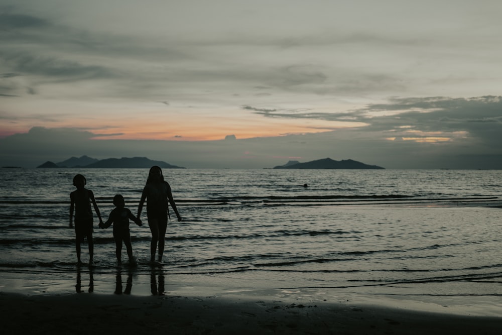 silhouette of people walking on beach during sunset