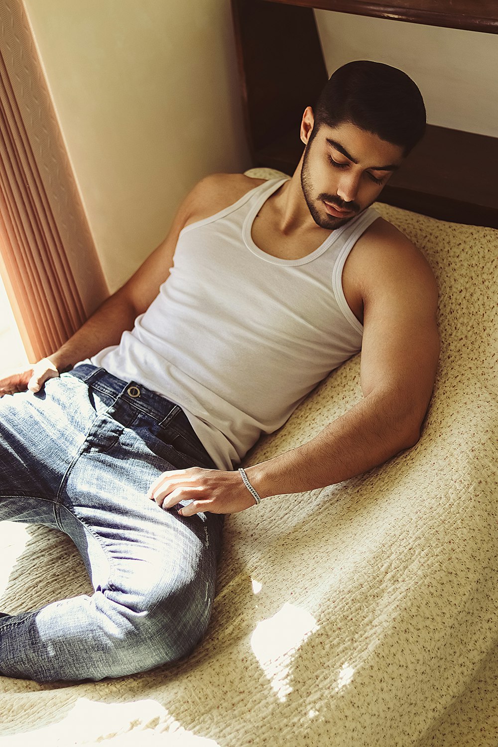 man in white tank top and blue denim shorts sitting on gray carpet