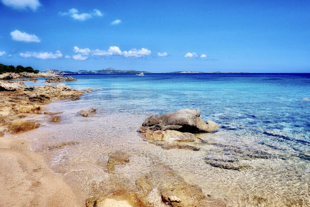 gray rock formation on sea under blue sky during daytime