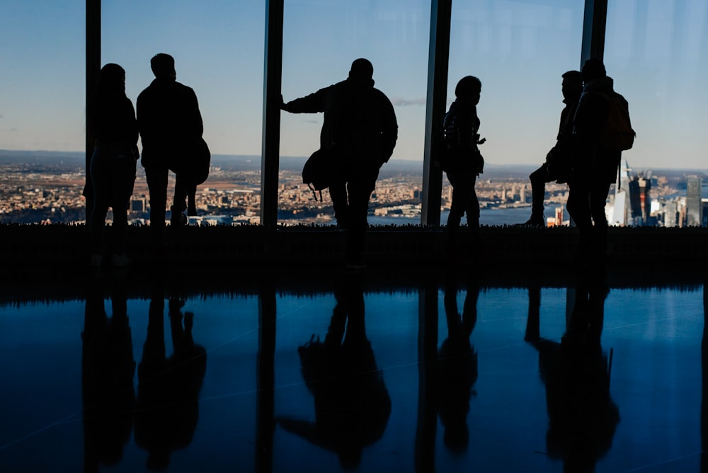 silhouette of people standing on glass window during daytime