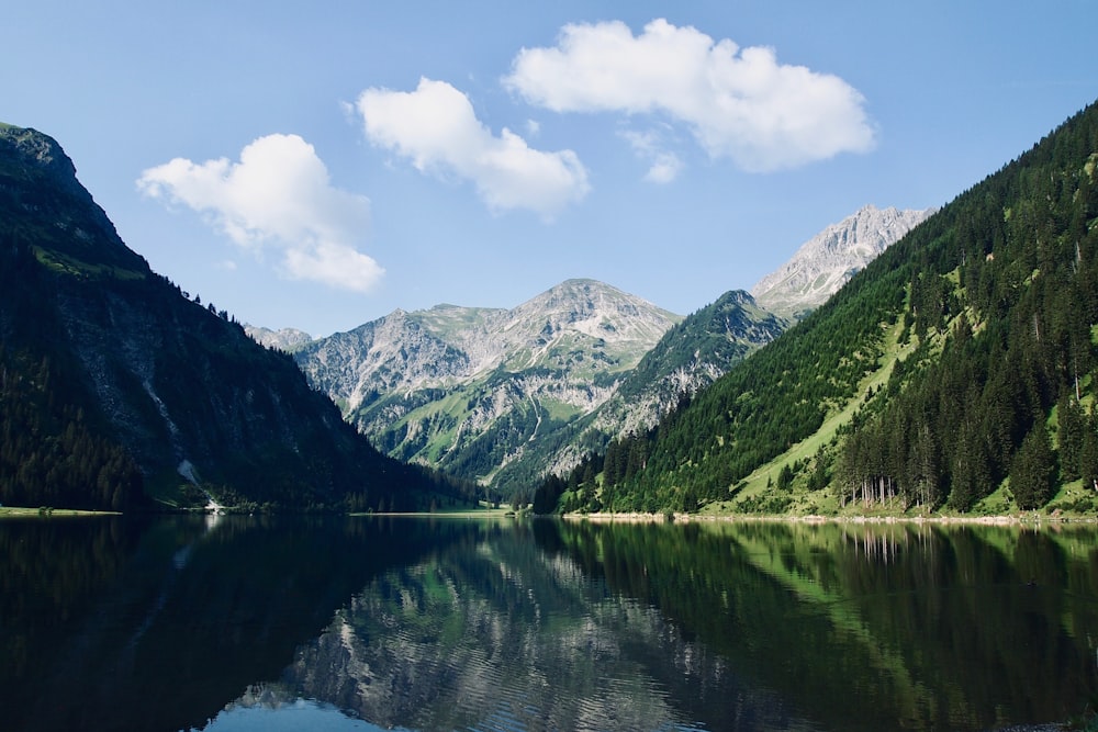 lake in the middle of green mountains during daytime