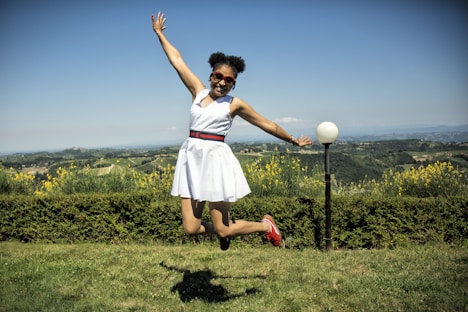 girl in white and pink dress standing on green grass field during daytime