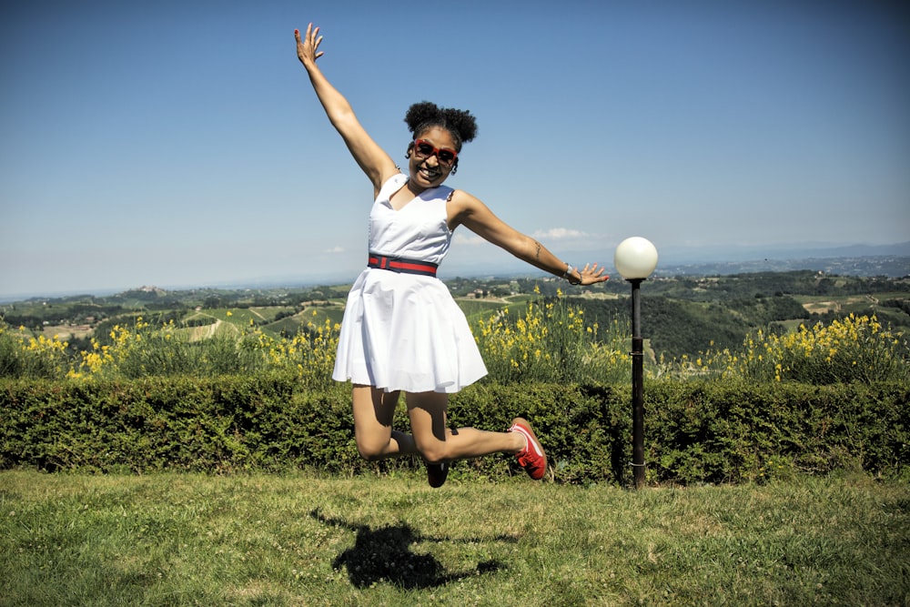 Ragazza in vestito bianco e rosa in piedi sul campo di erba verde durante il giorno