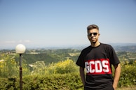 man in black crew neck t-shirt standing on green grass field during daytime