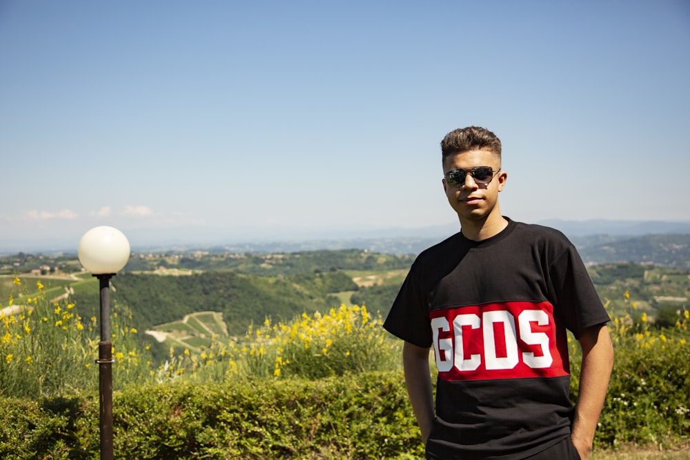 homme en noir ras du cou T-shirt debout sur le terrain d’herbe verte pendant la journée