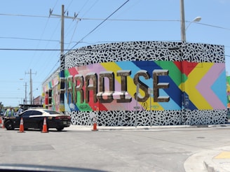 black sedan parked beside blue and yellow wall
