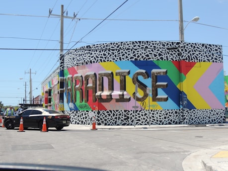 black sedan parked beside blue and yellow wall