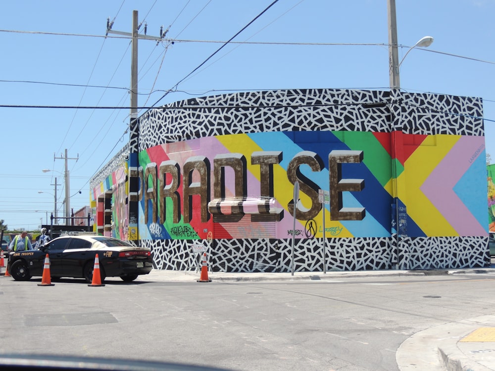 black sedan parked beside blue and yellow wall