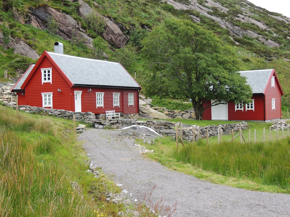 red and white wooden house near green grass field and mountain during daytime