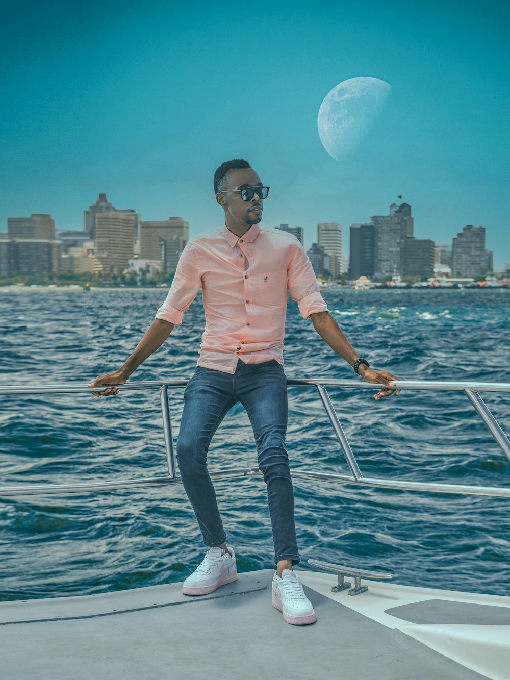 man in pink dress shirt and blue denim jeans standing on boat during daytime