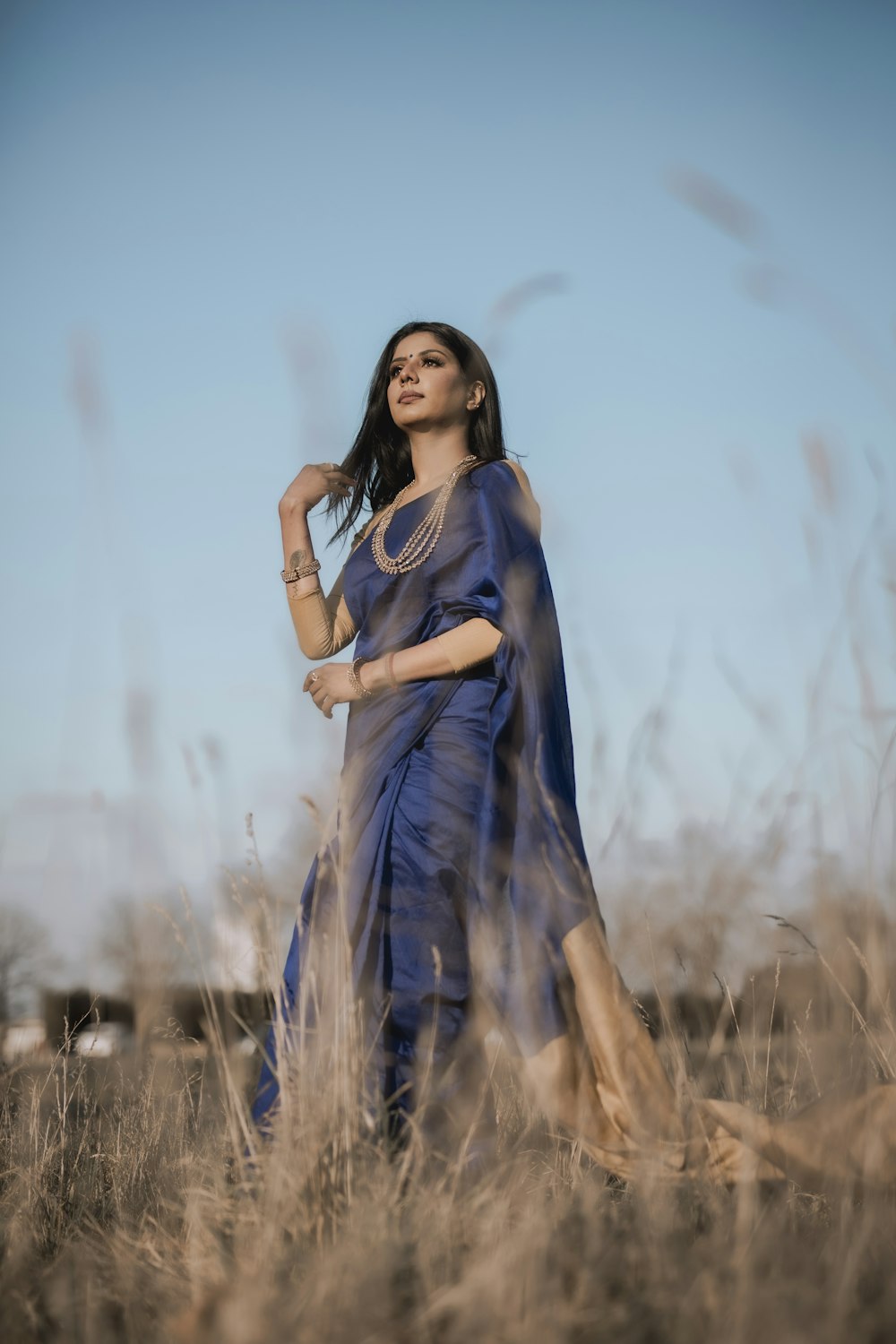 woman in blue dress standing on brown grass field during daytime