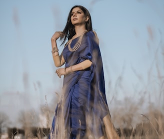 woman in blue dress standing on brown grass field during daytime