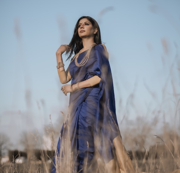 woman in blue dress standing on brown grass field during daytime