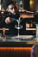man in black suit jacket holding clear wine glass