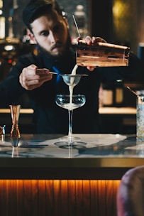 man in black suit jacket holding clear wine glass