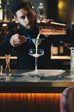 man in black suit jacket holding clear wine glass
