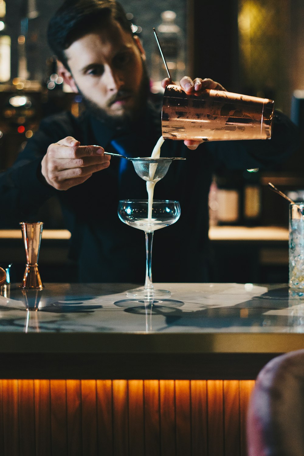 man in black suit jacket holding clear wine glass