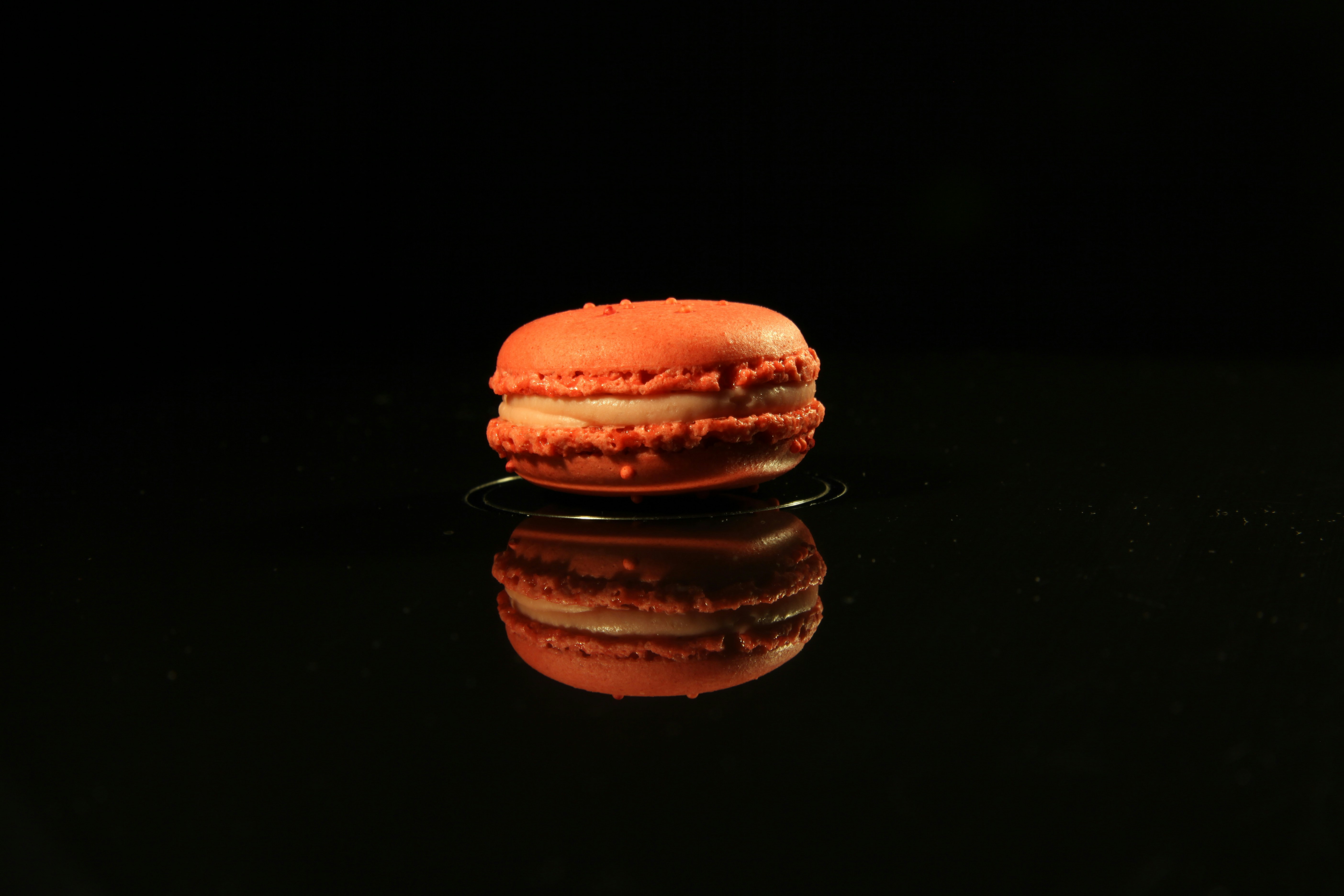 Single orange macaron on black