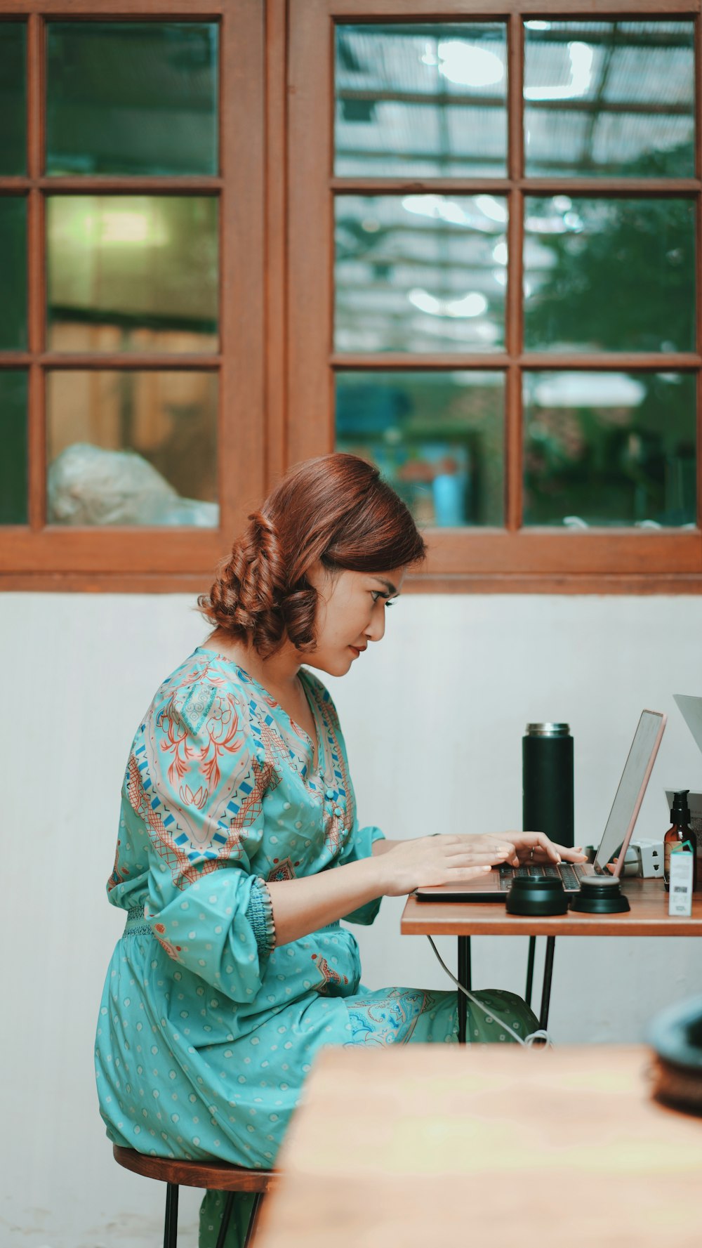 Frau in grün-weißem geblümtem Langarmshirt mit Computer