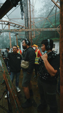 man in black t-shirt and gray pants holding black dslr camera