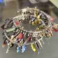 A collection of colorful keychains and small decorative trinkets attached to a circular metal band. The items include small keys, abstract shapes, and various metallic and painted charms in bright colors like red, yellow, and blue. The arrangement creates a visually striking mix of textures and forms.