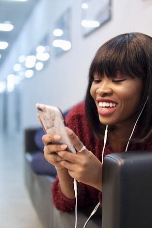 A satisfied customer holding a repaired phone with a smile in a cozy living room.