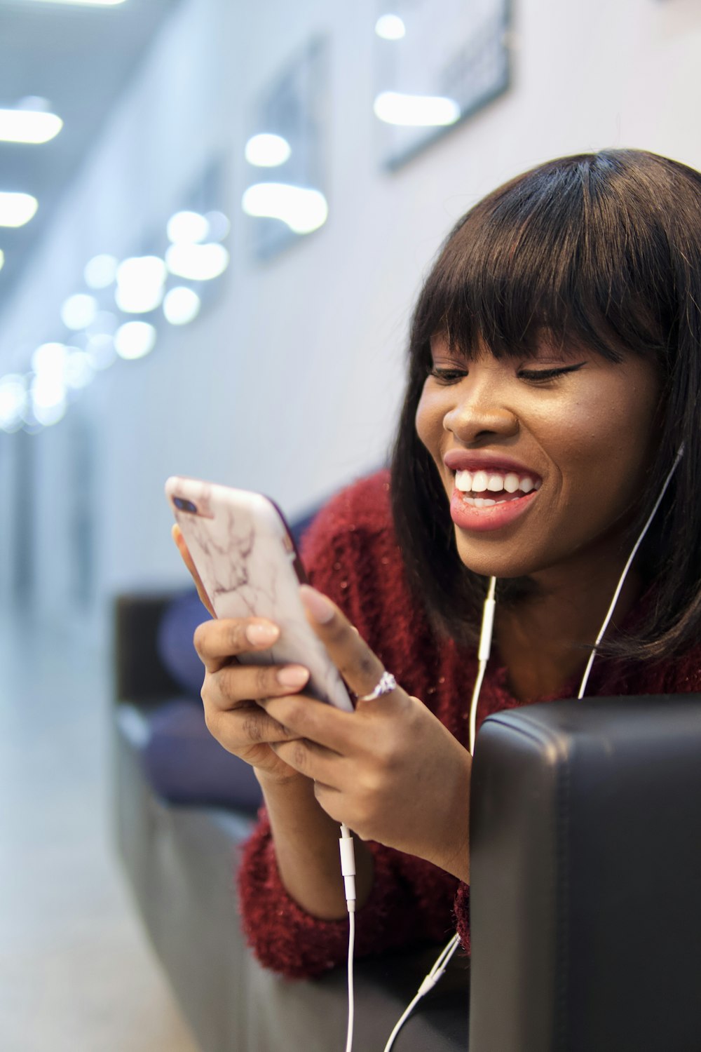 mulher na camisa cor-de-rosa que segura o smartphone branco