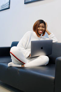 A confident student smiling while researching online MBA options on a laptop in a cozy home setting.