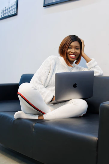 A confident student smiling while researching online MBA options on a laptop in a cozy home setting.