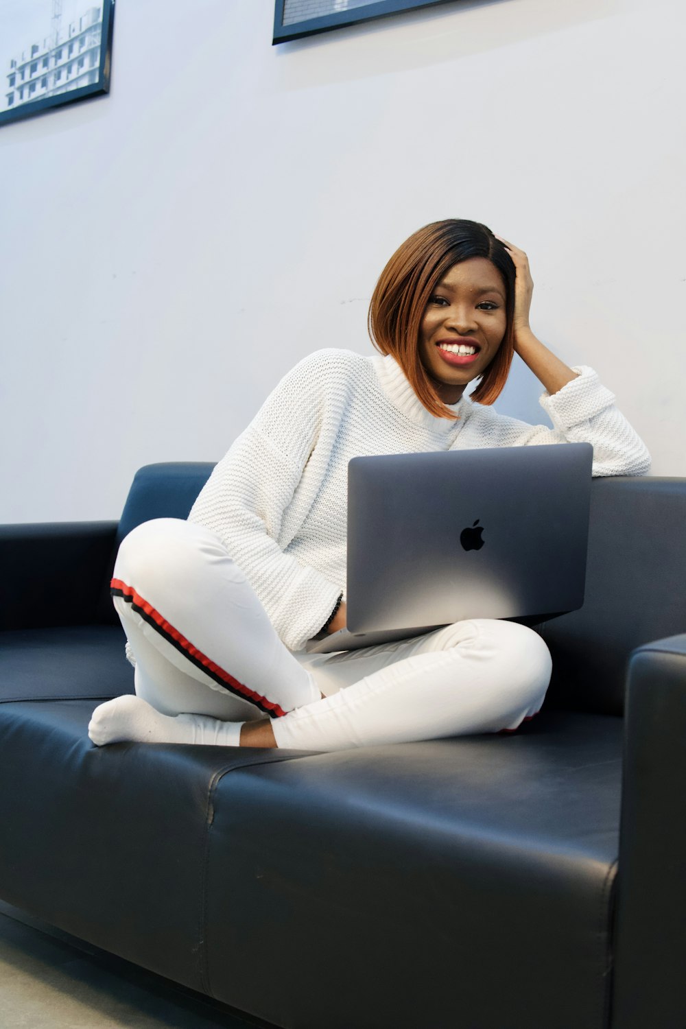 woman in white sweater and white pants sitting on blue couch