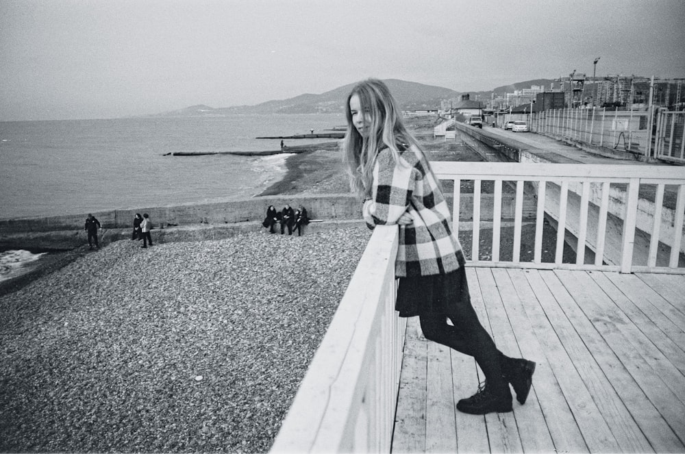 woman in plaid coat standing on concrete bridge