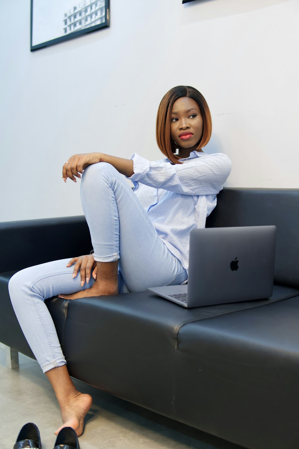 woman in white sweater and blue denim jeans sitting on gray couch