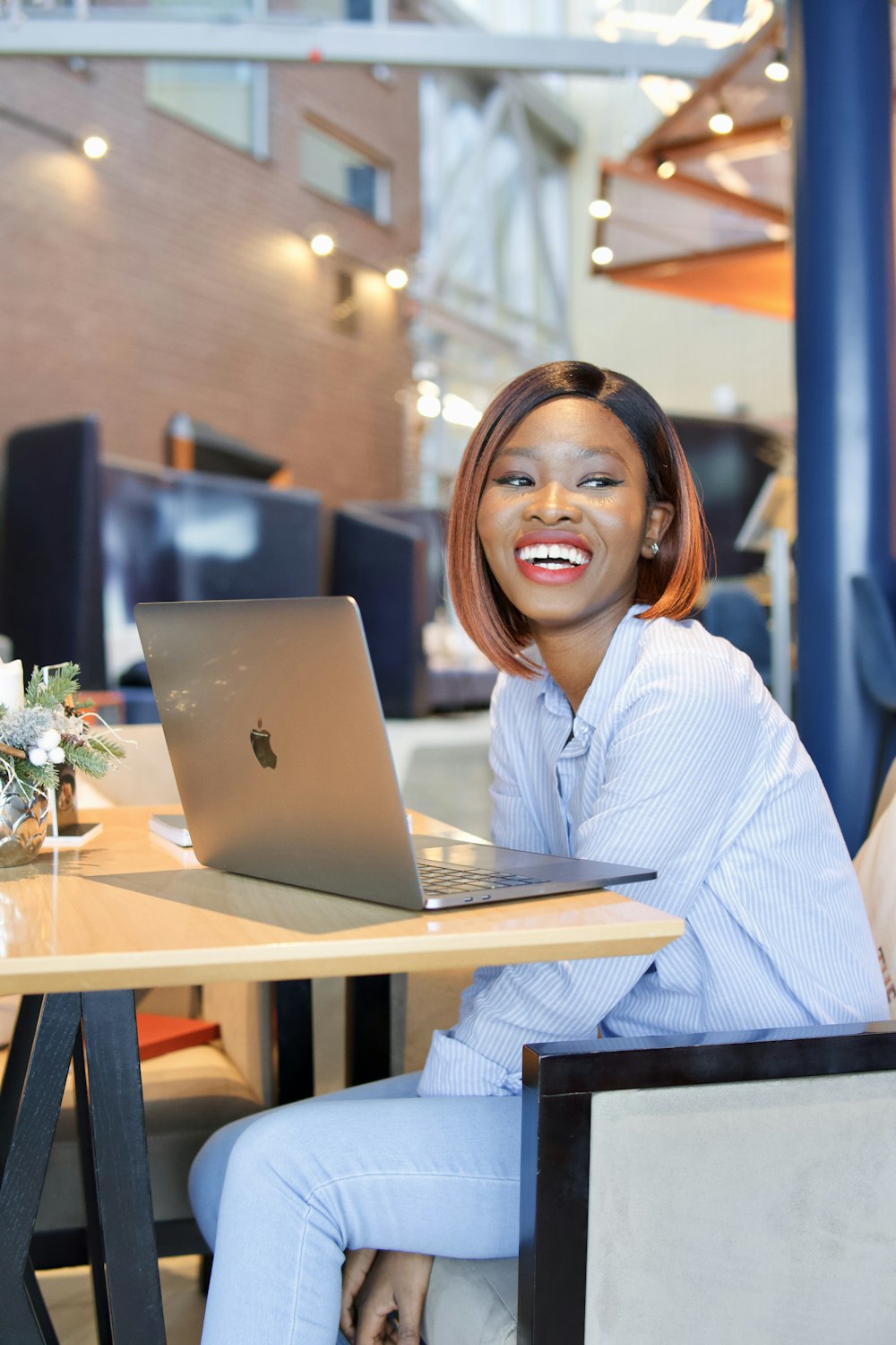 smiling woman in white dress shirt using macbook