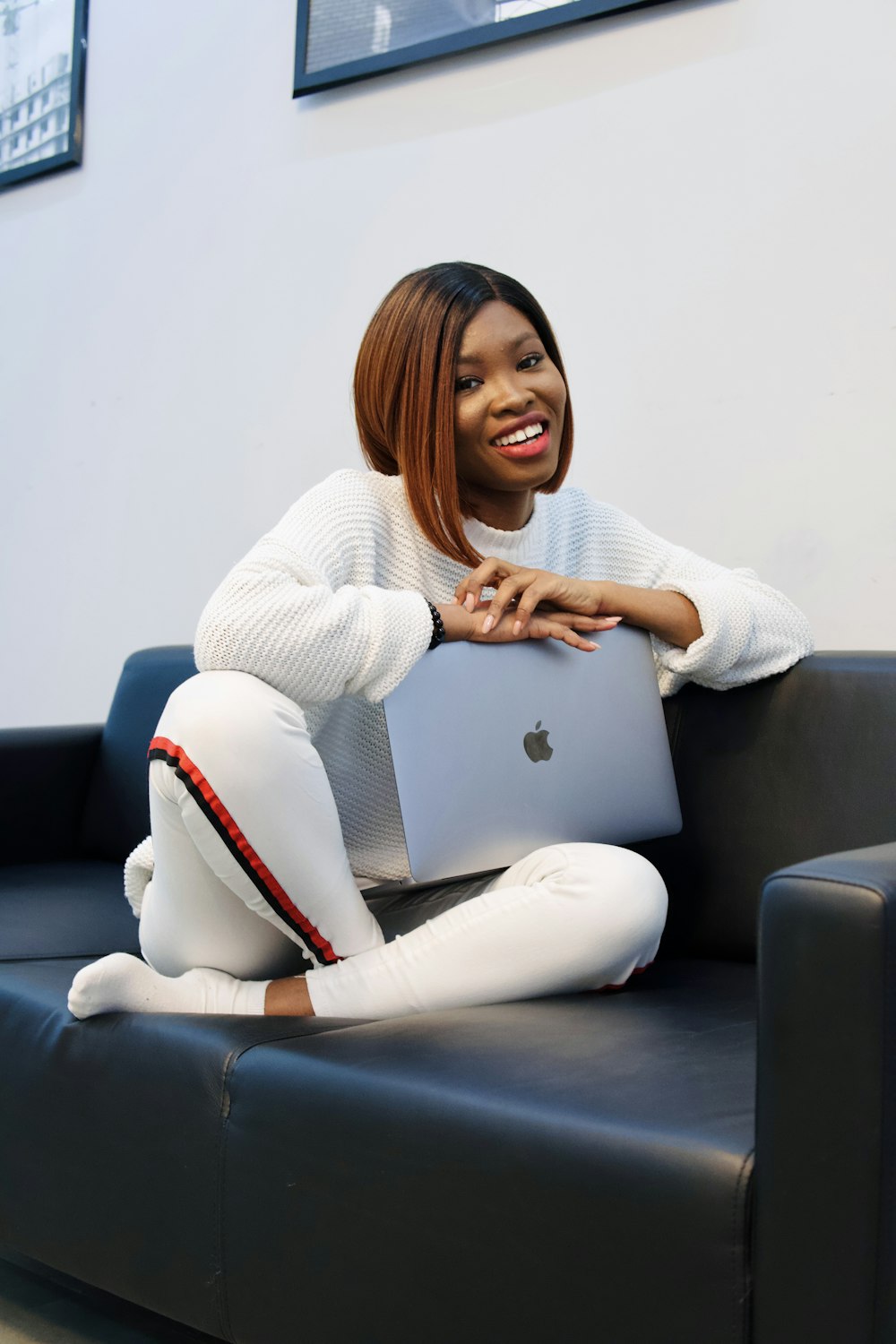 woman in white sweater and white pants sitting on gray couch