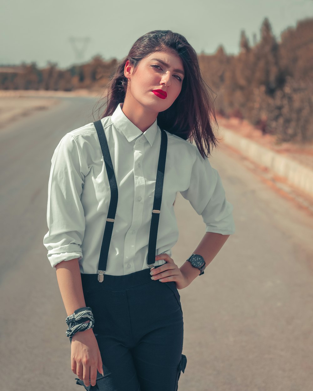 흰색 버튼 업 셔츠와 검은 바지를 입은 여자가 낮 동안 도로에 서 있다