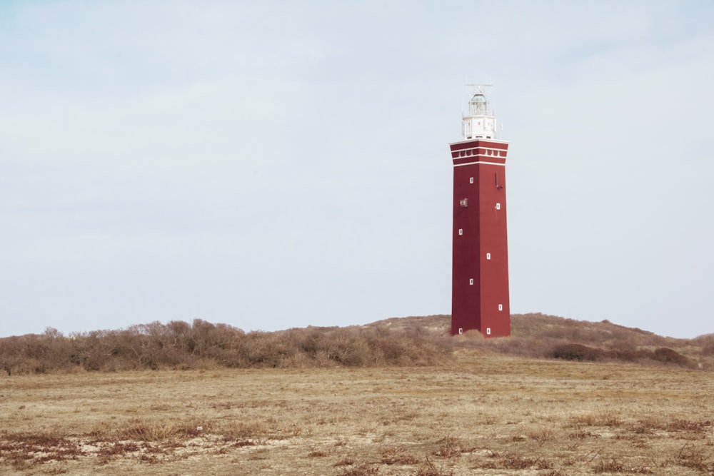 a red and white light house in the middle of a field