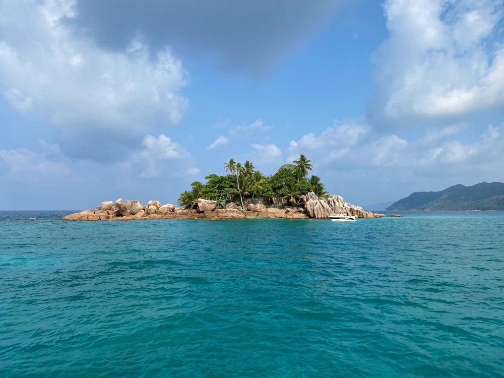 green trees on island surrounded by water under blue sky and white clouds during daytime