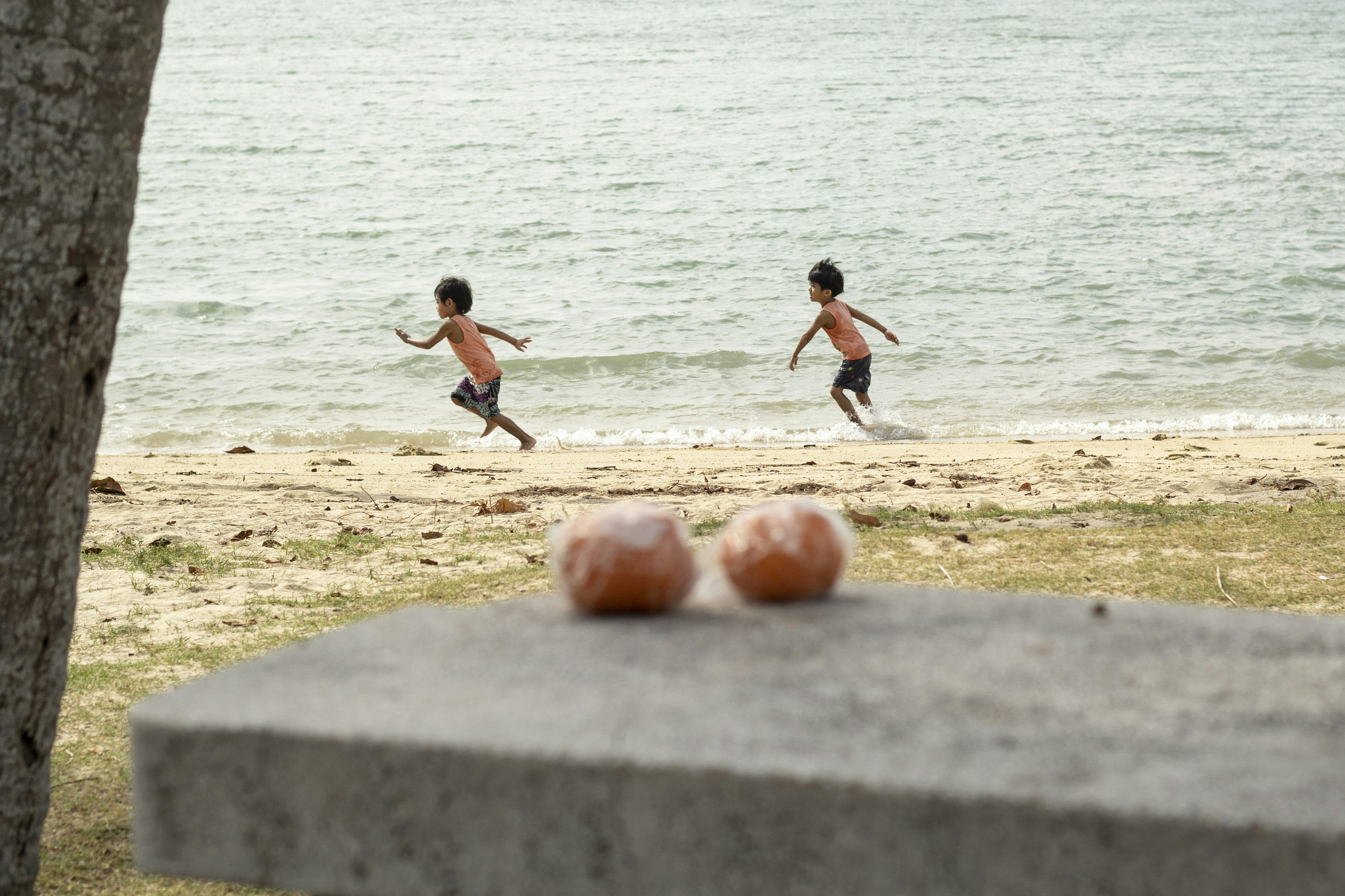 3 boys playing soccer on beach during daytime