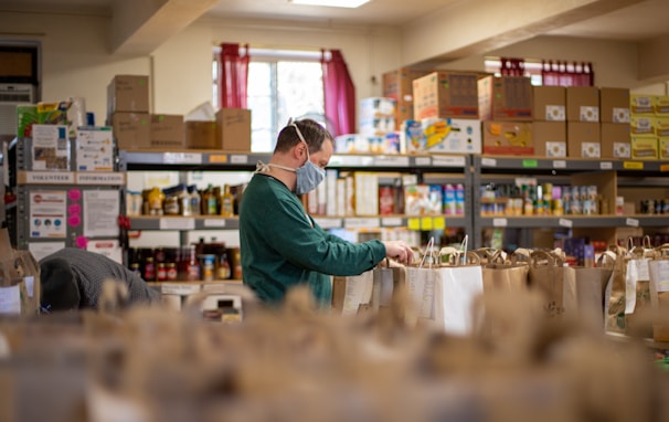 A group of volunteers packing food boxes in a bright, organized warehouse.