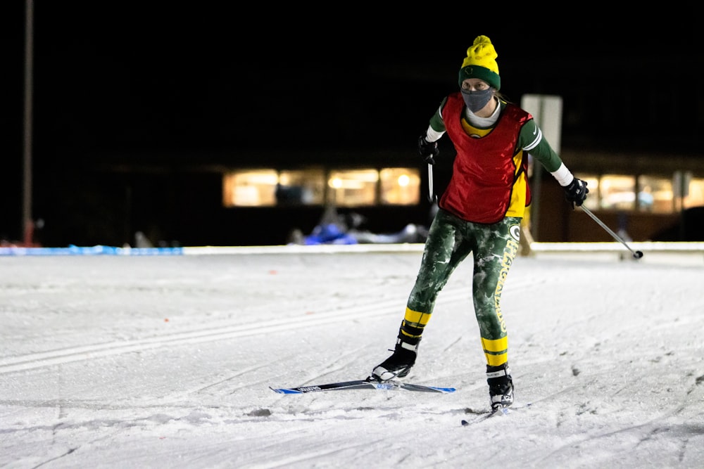person in red and black jacket and green pants riding on snow board during daytime