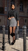 woman in black blazer and black and white skirt standing beside black metal stand