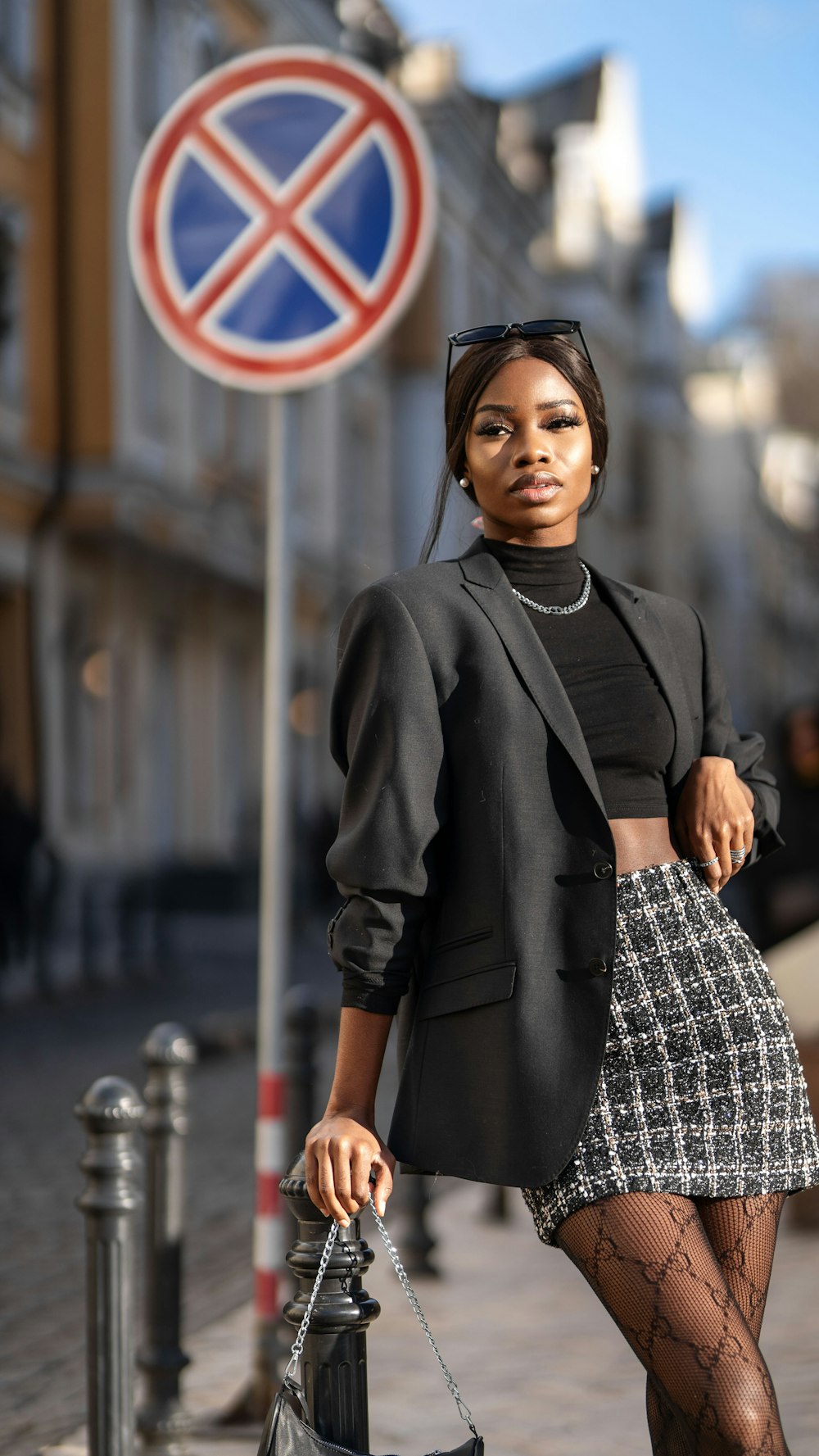 mulher no blazer preto que está perto da sinalização branca e azul