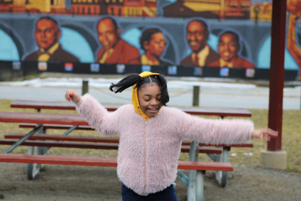 A young girl twirling happily in a bright, playful outfit from Prisma's kids' collection in a park.