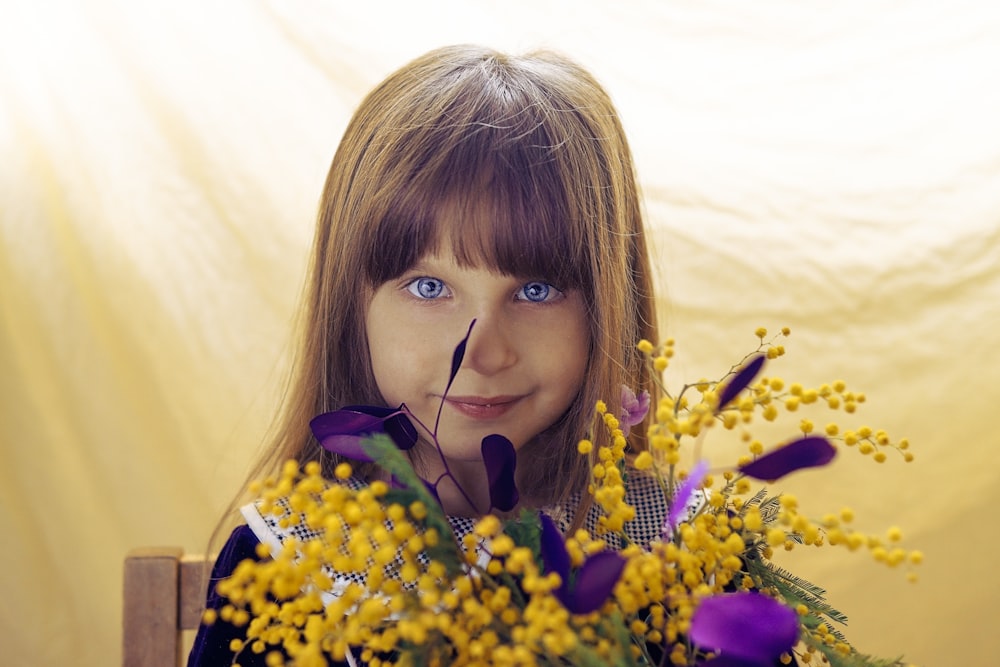 girl with blonde hair holding yellow flowers