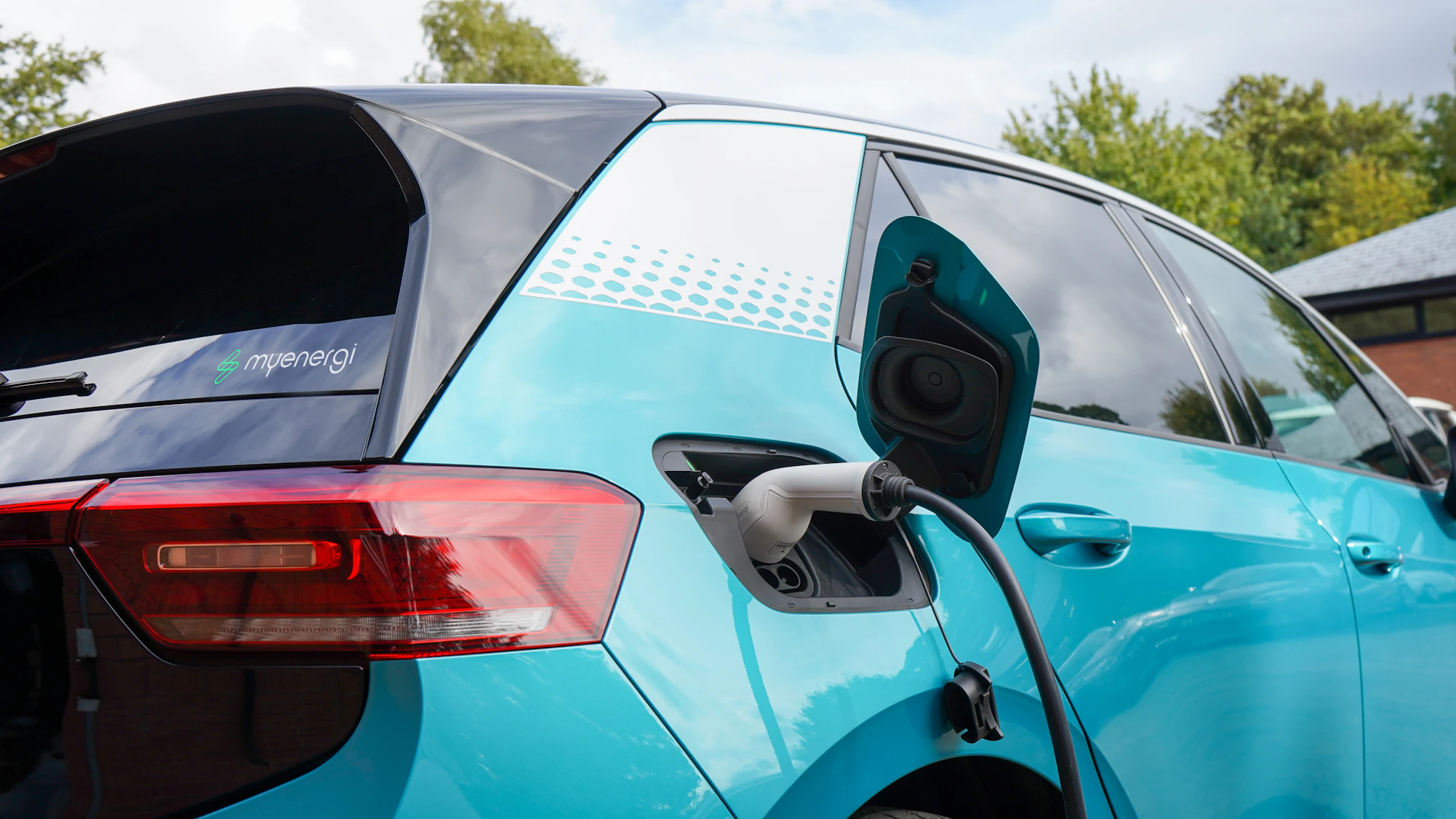 Auto eléctrico celeste conectado a un cargador