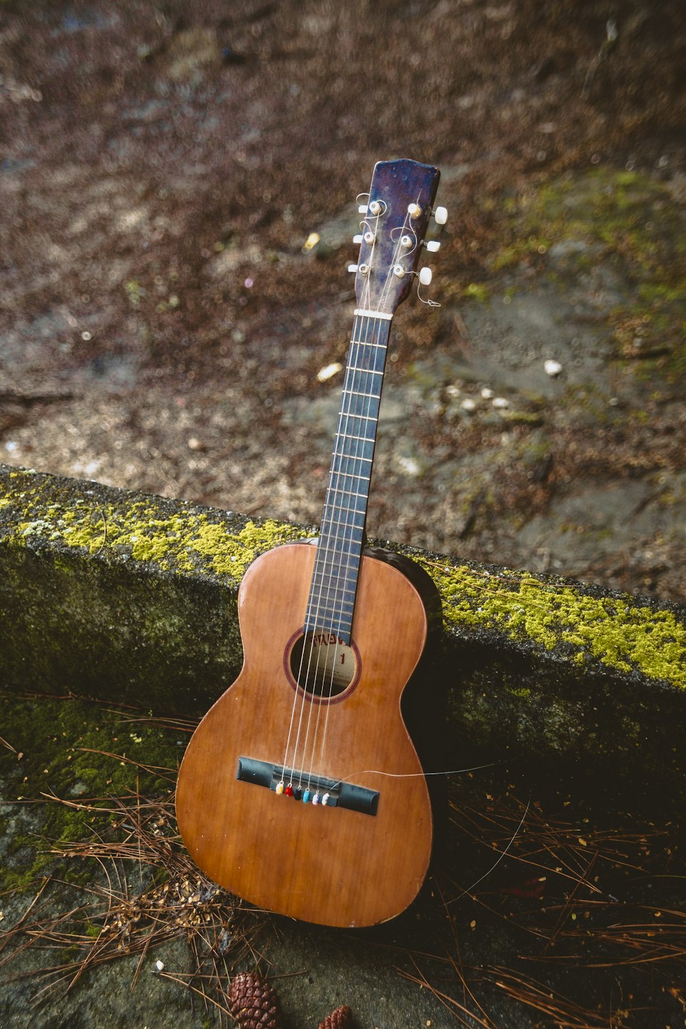 brown acoustic guitar on rock